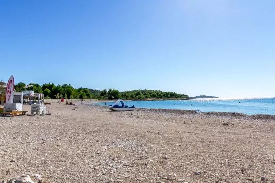 Oblázková pláž s pozvolným vstupem do moře.