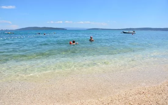 Oblázková pláž s pozvolným vstupem do moře v městě Kaštel Stari.