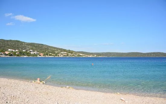 Oblázková pláž s pozvolným vstupem do moře.