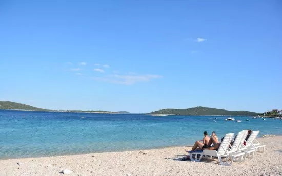 Oblázková pláž s pozvolným vstupem do moře.