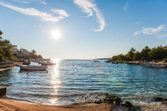 Menší oblázková pláž s betonovými deskami 150 m od objektu.