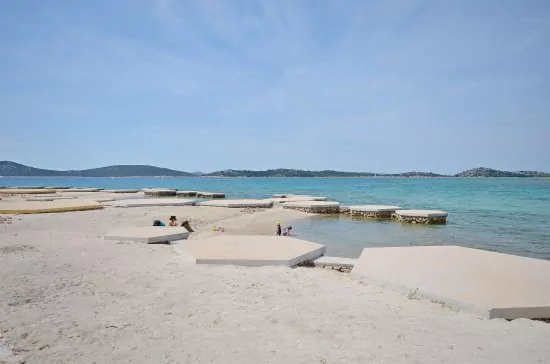 Písčitá pláž doplněná o betonové desky ve městě Vodice.
