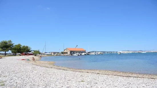 Sukošan - oblázková pláž podél pobřeží.