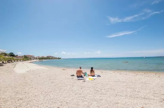 Oblázková pláž s pozvolným vstupem do moře.