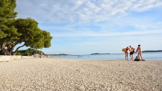 Oblázková pláž Fažana s pozvolným vstupem do moře.