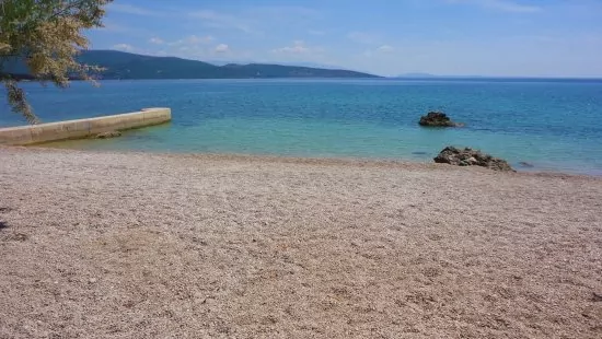 Oblázková pláž s pozvolným vstupem do moře.